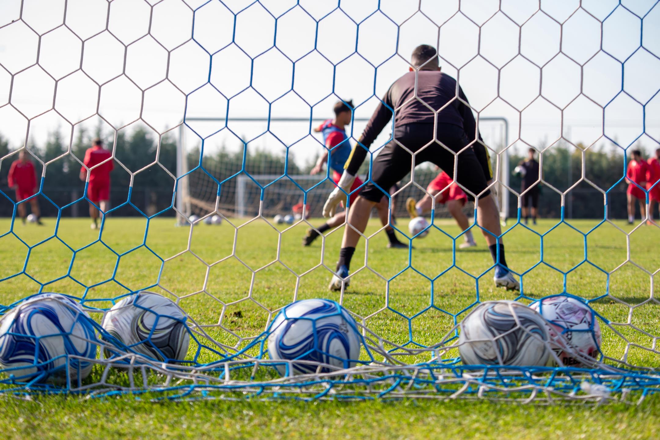 soccer-ball-on-field-behind-view-of-net-team-tra-2024-12-07-15-29-49-utc