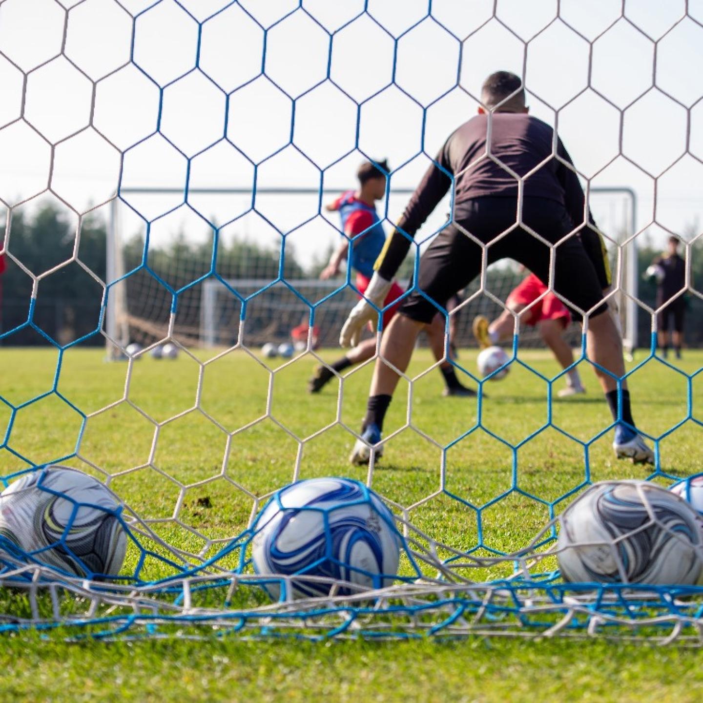 soccer-ball-on-field-behind-view-of-net-team-tra-2024-12-07-15-29-49-utc
